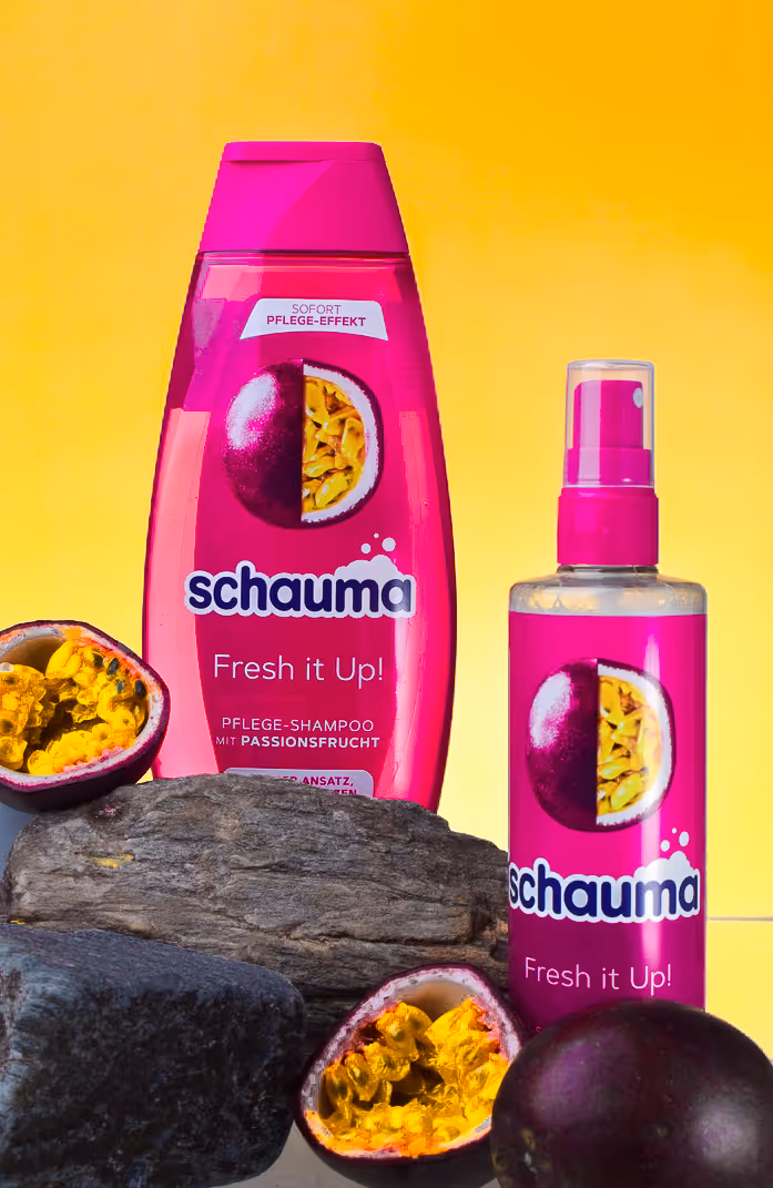 Schauma Fresh it Up shampoo and spray with passion fruit and stones on bright yellow background.