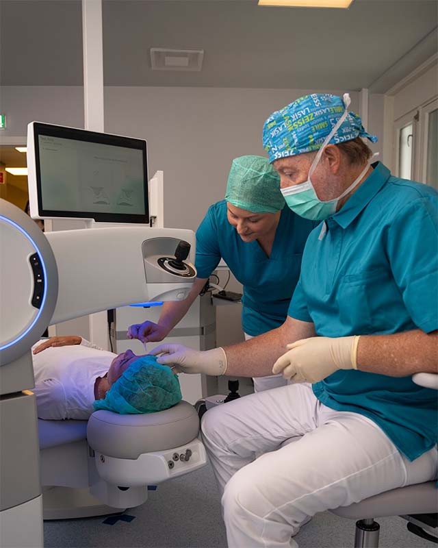 Øyekirurg Willy Pettersen og sykepleier drypper bedøvende øyedråper i øyet på pasient under synskorrigerende laseroperasjon hos OSLO SYN