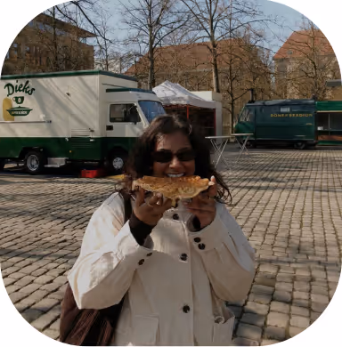 Student eating a fresh waffle at the Domplatz market in Münster, a popular local tradition.