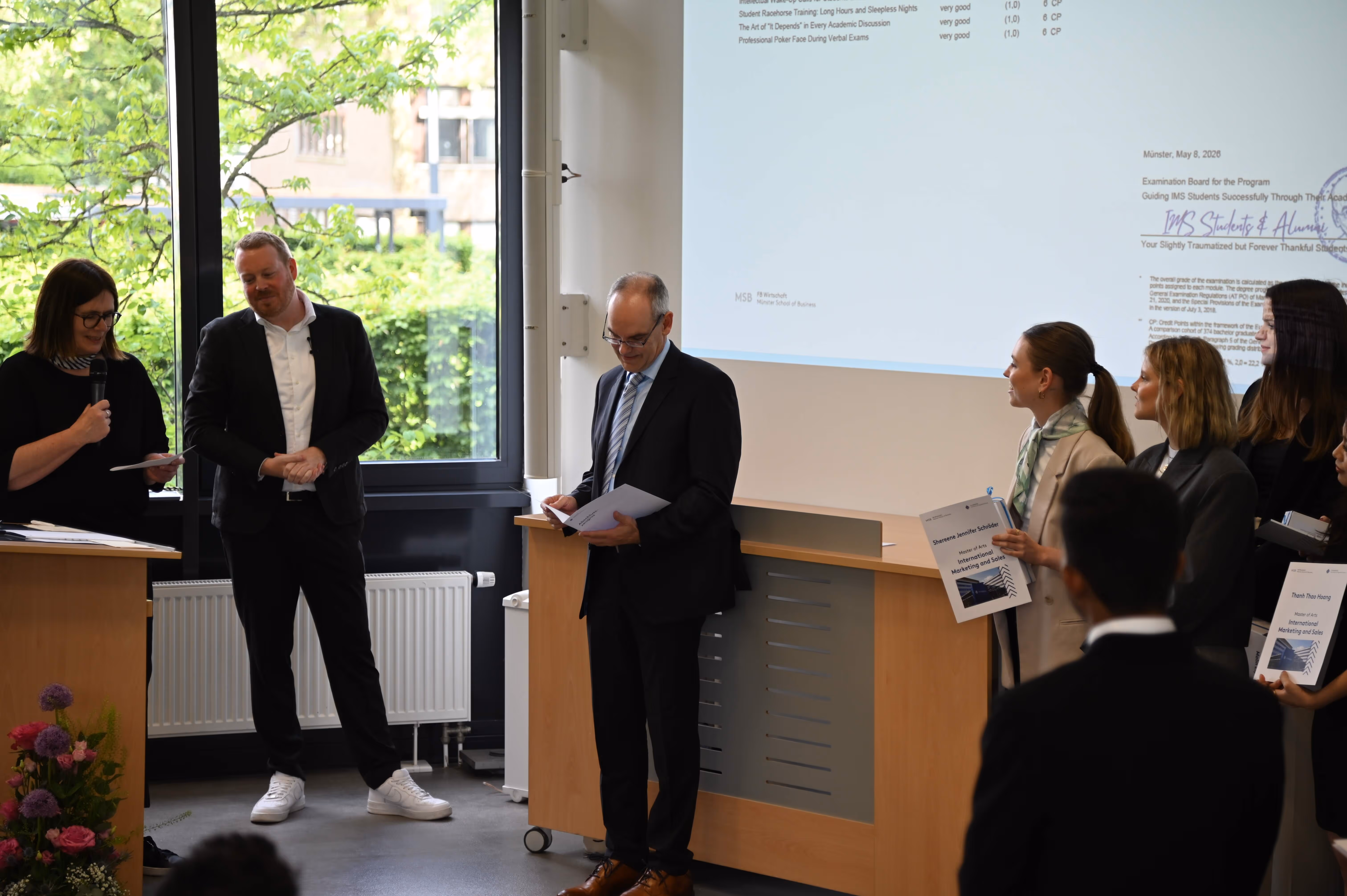 IMS graduate receiving a certificate from faculty members during the graduation ceremony.