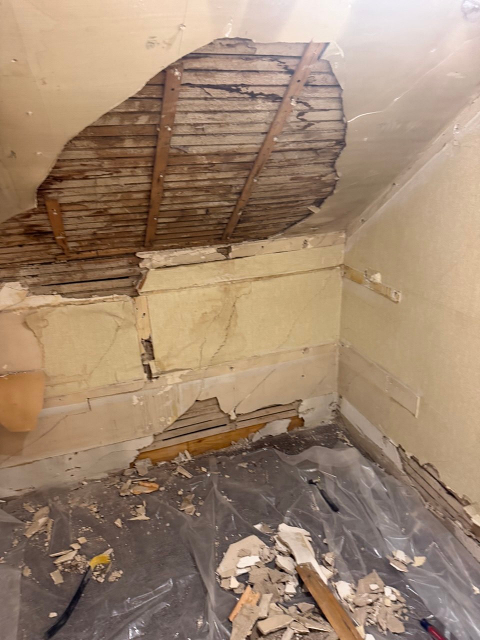 Damaged plaster on a sloped ceiling and walls with exposed wood lath before repair in Guilford, CT