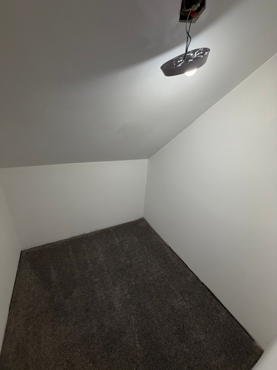 Smooth white sloped ceiling and walls after repair in Guilford, CT, with the light fixture still detached