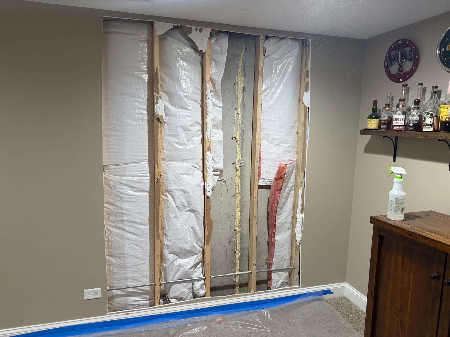 Open wall with exposed framing, insulation, and concrete before drywall repair in Lemont, IL