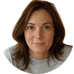 Portrait of a woman with brown hair and brown eyes wearing a gray shirt, looking directly at the camera.