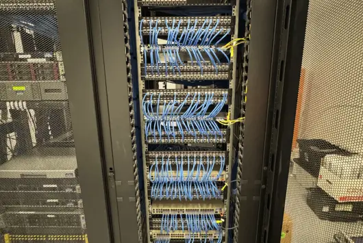 Server rack with organized blue Ethernet cables connected to multiple patch panels inside a data center.