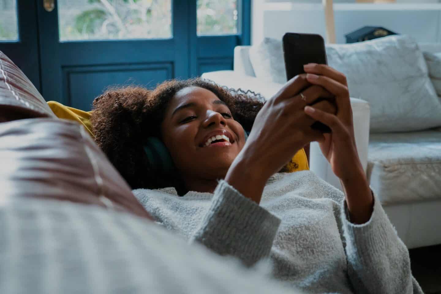 Woman laying on a couch using her mobile phone