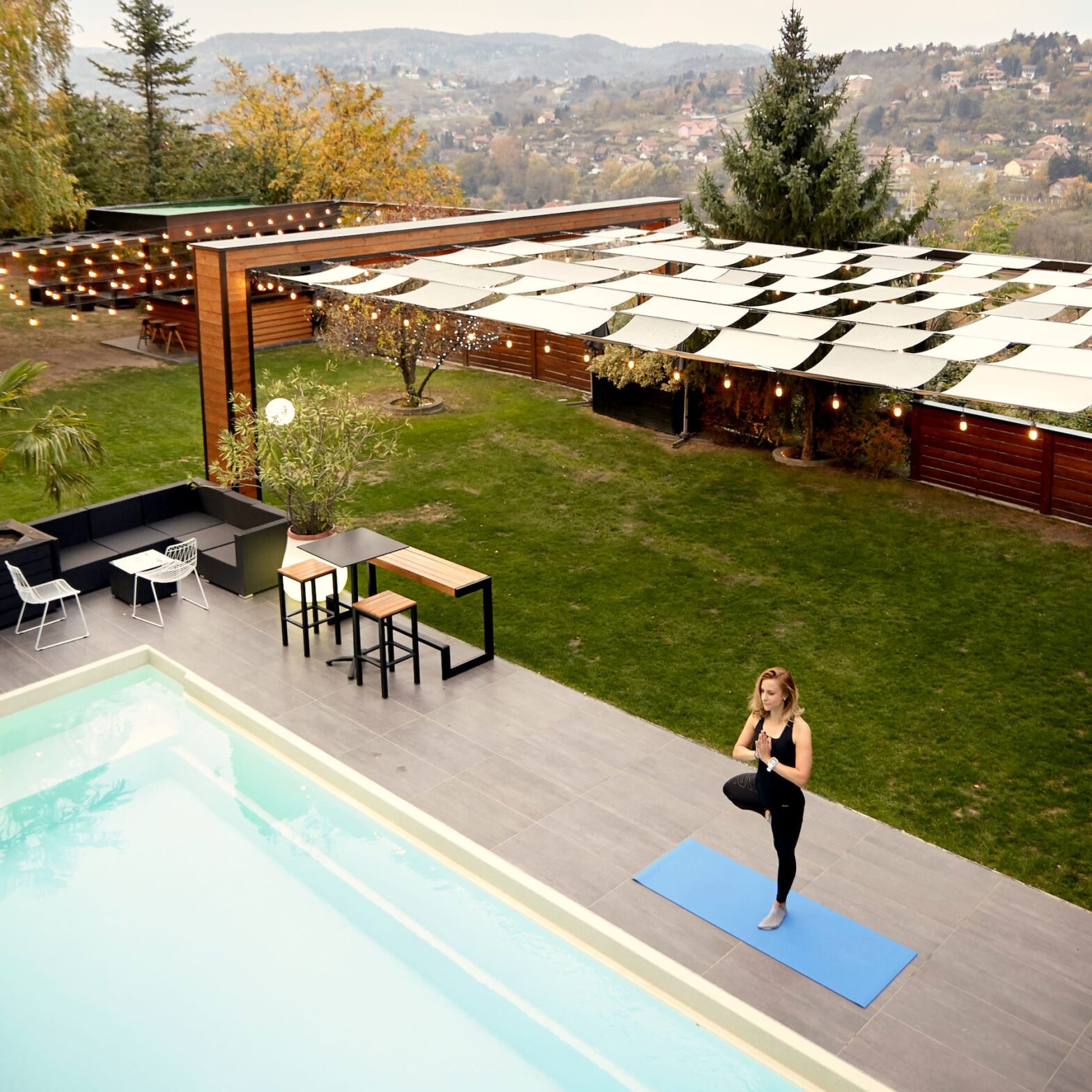 Woman meditating in her backyard next to a pool