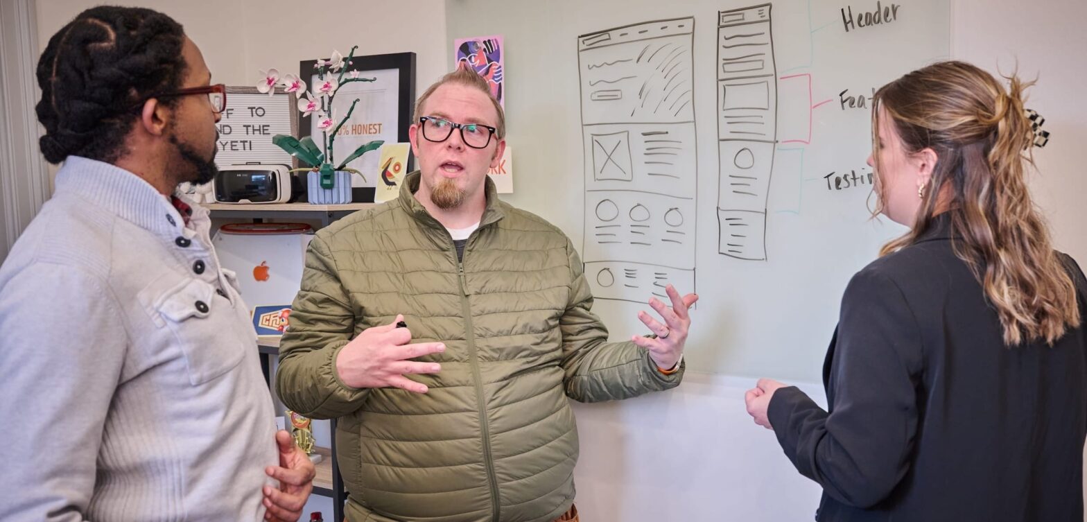 Team discussing a website layout in front of a whiteboard