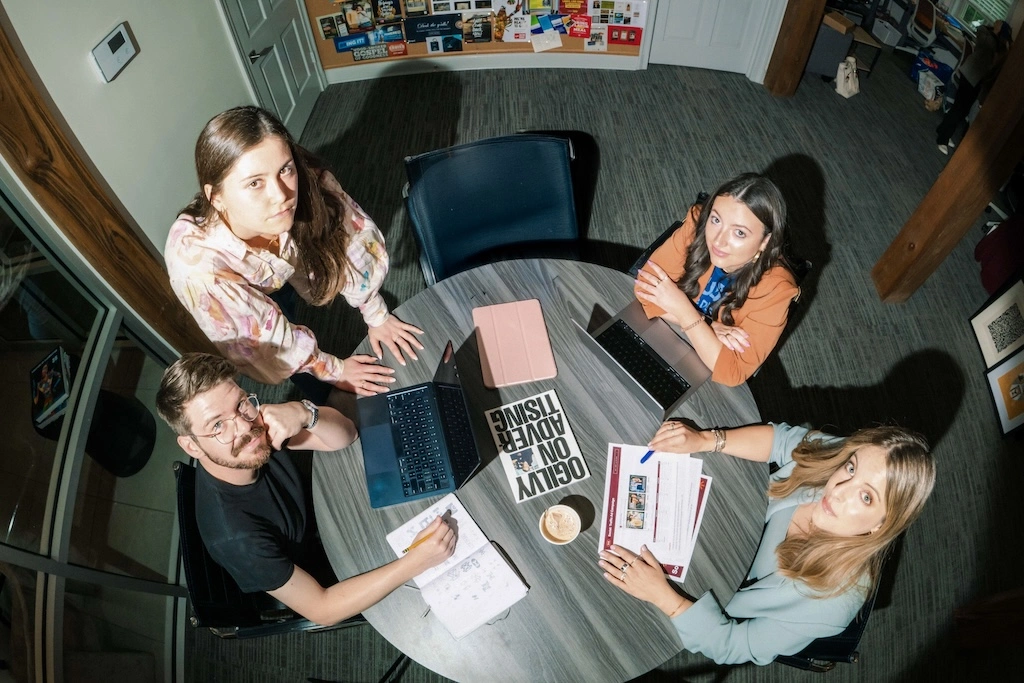 An overhead shot of a team sitting at a conference room table looking up