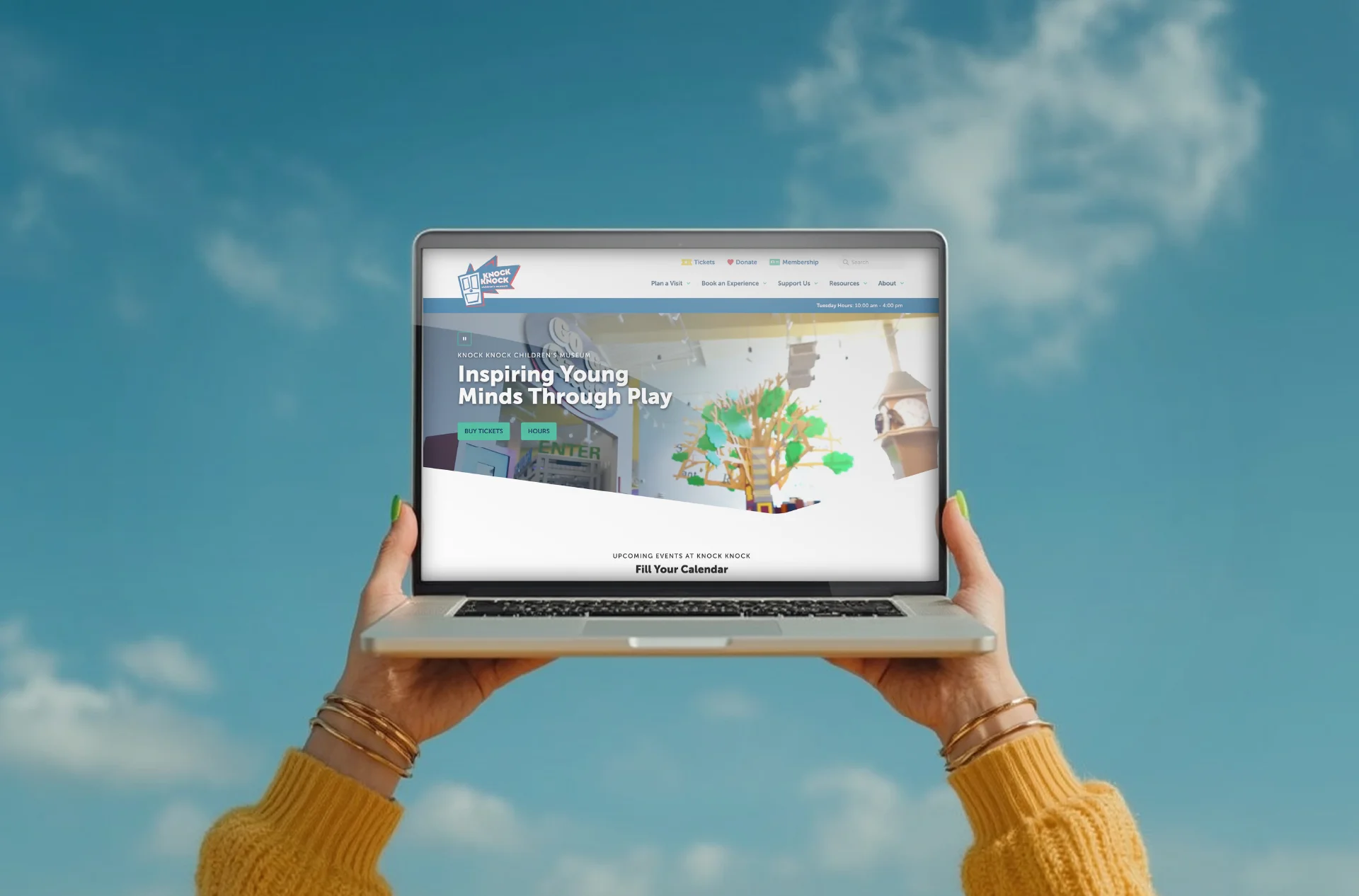 Person holding a laptop with the Knock Knock Museum website loaded