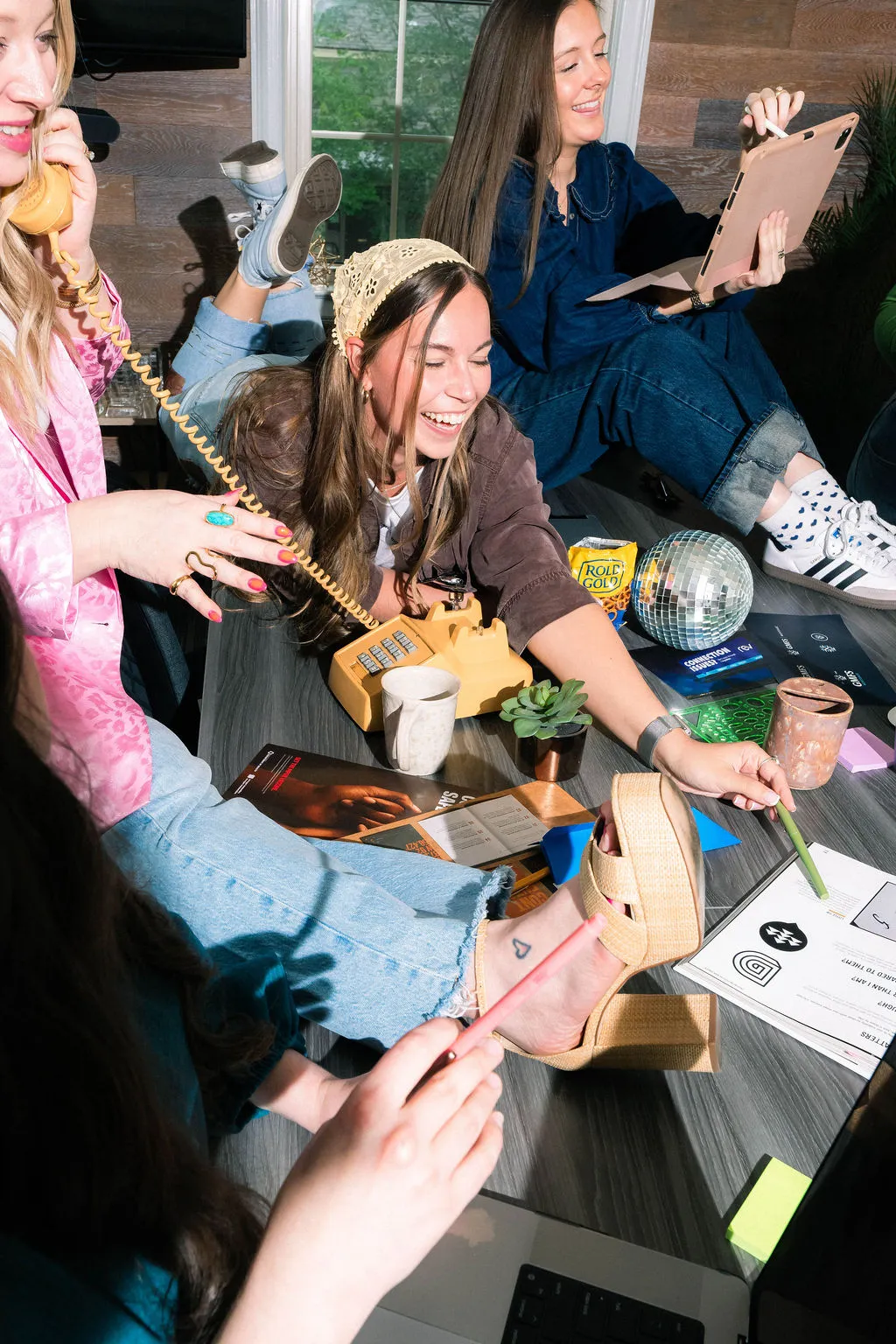 An overhead view of team members laughing around a table scattered with a banana phone, a disco ball and design samples