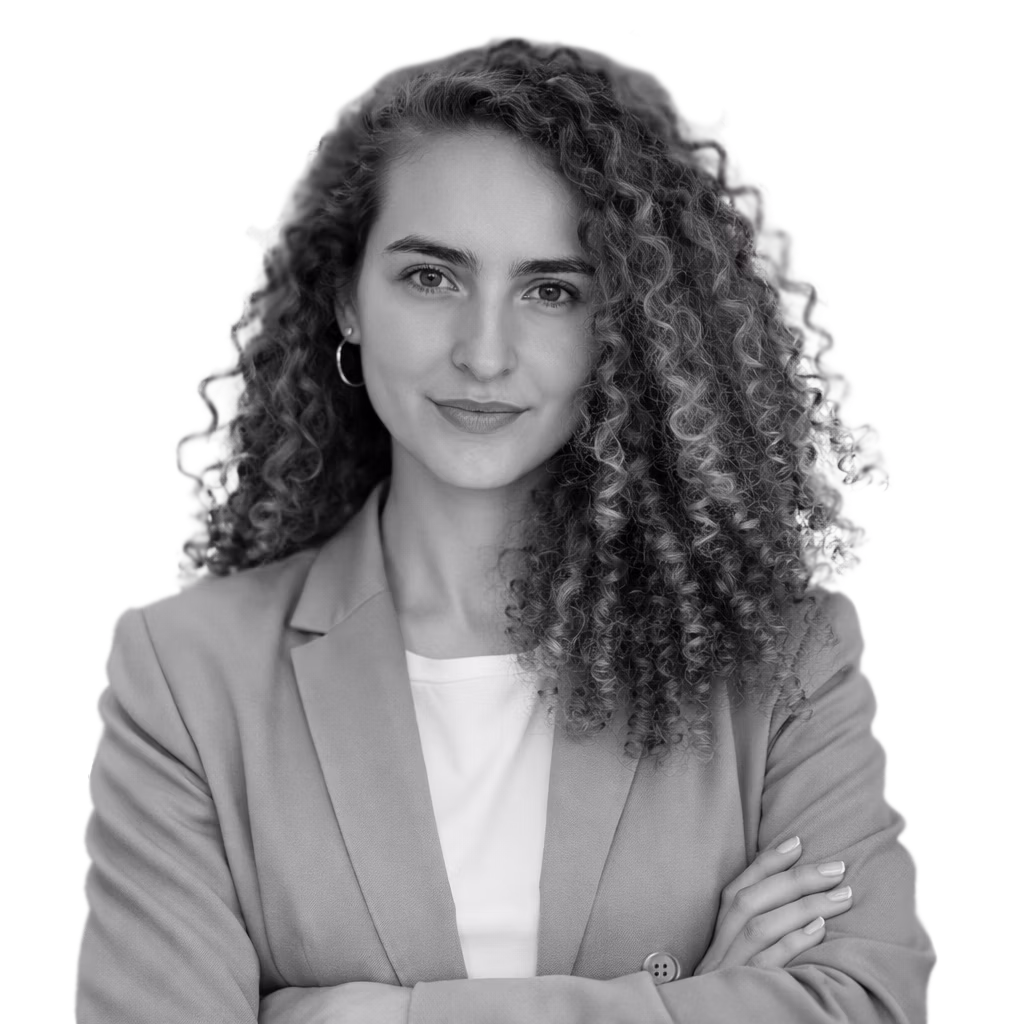 Confident woman with curly hair wearing a blazer and white shirt, arms crossed, facing forward.
