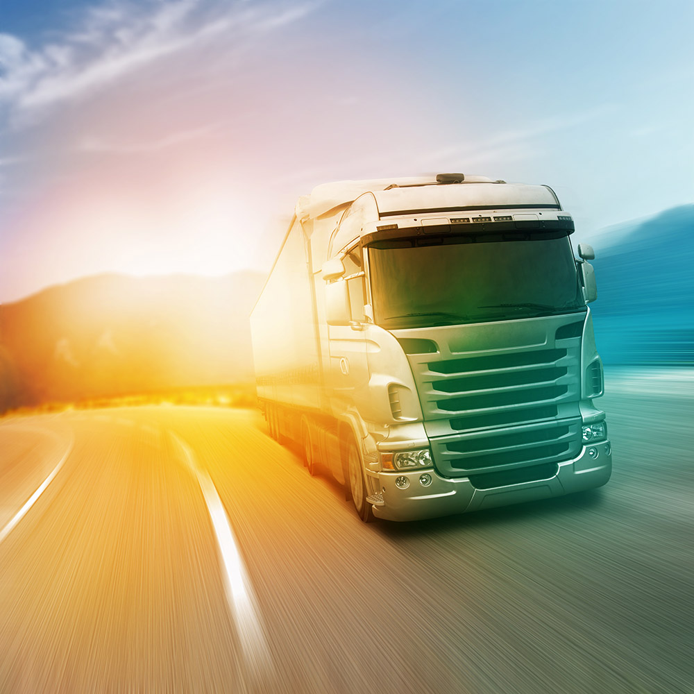 White semi-truck driving fast on a curved highway at sunrise with blurred motion effect.