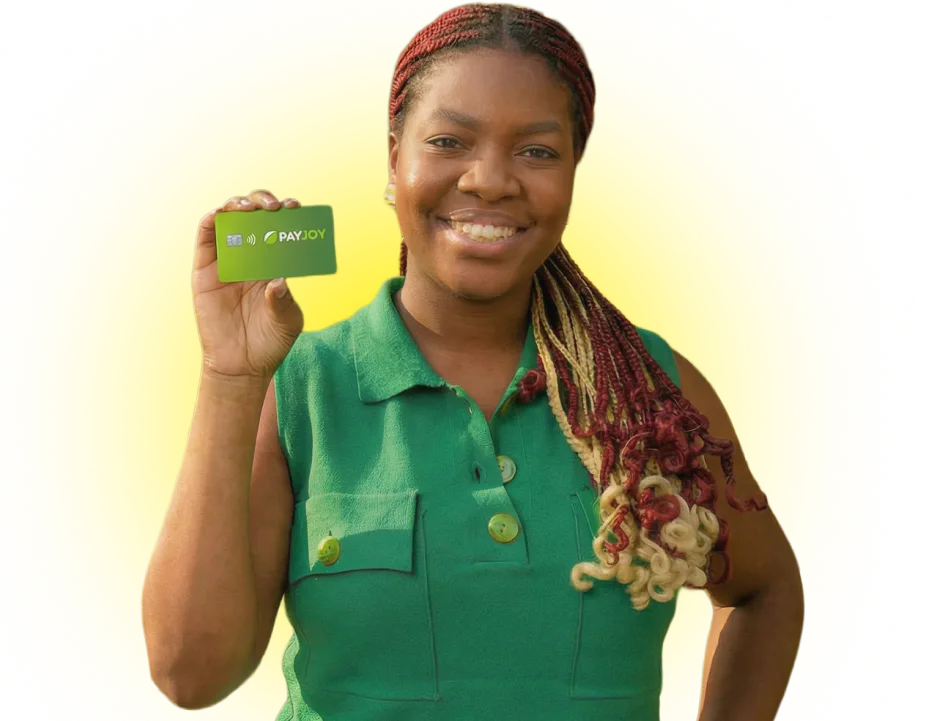 Smiling woman with red and blonde braids holding a green PayJoy card against a yellow background.