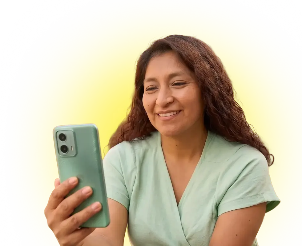 Smiling woman with curly hair looking at her smartphone against a bright yellow background.