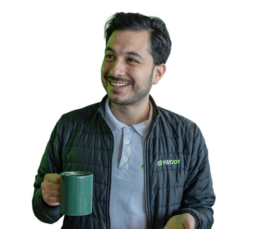 Smiling man wearing a black PayJoy jacket holding a green ceramic mug.
