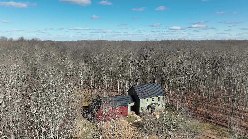 Dark bronze standing seam metal roof on a farmhouse framed by treeline in Columbia, Tennessee