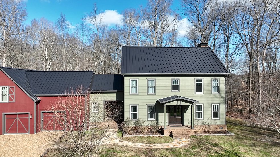 Side view of a dark bronze standing seam metal roof on a rural farmhouse in Columbia, Tennessee