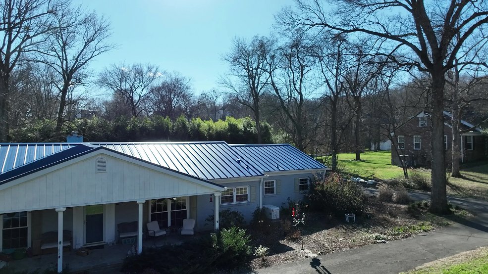 Royal blue standing seam metal roof and low slope eave on a mid century house in Nashville, TN