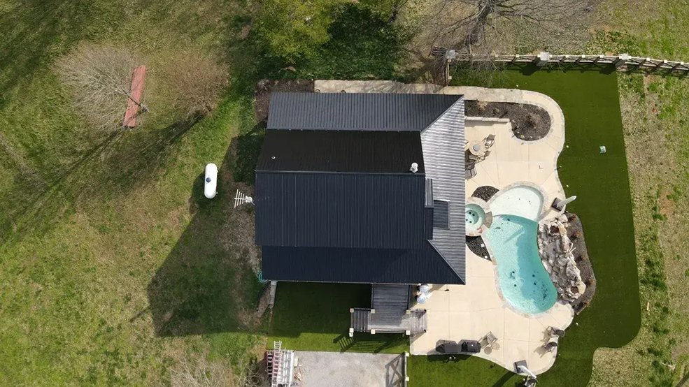 Black classic wave panel metal roof on a wooded log cabin in Sparta, TN