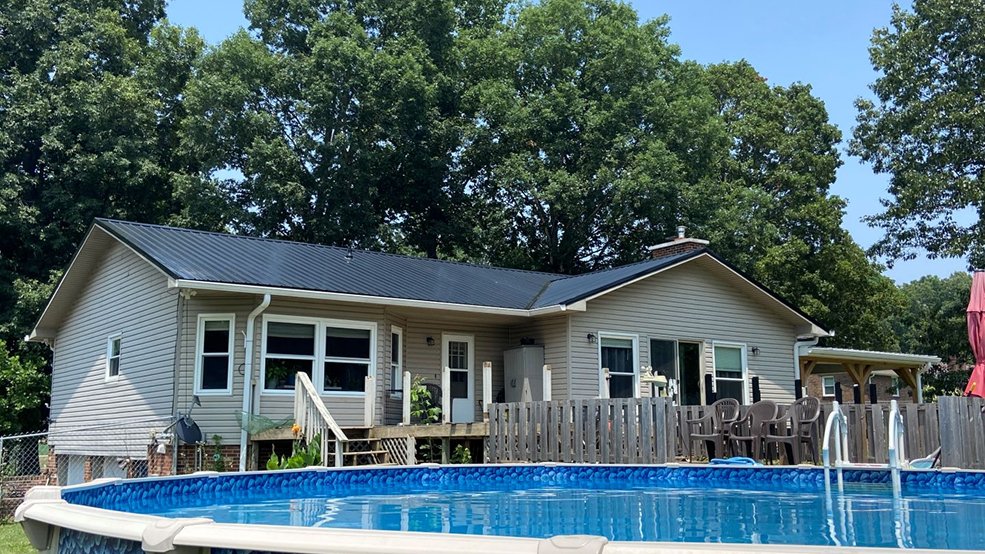 Black classic panel metal roof and long ridge line on a grassland ranch home in Smyrna, Tennessee