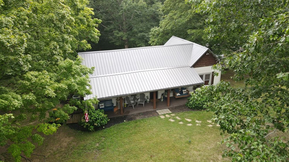 Silver classic panel metal roof and gable on a forest home in Centerville, Tennessee