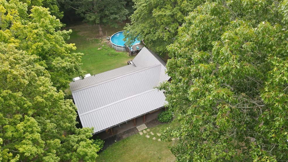 Silver classic panel metal roof under tree cover in Centerville, TN
