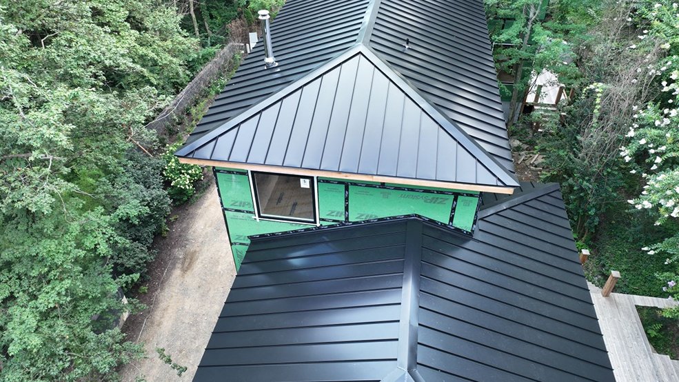 Black standing seam metal roof on a home among trees in McMinnville, Tennessee