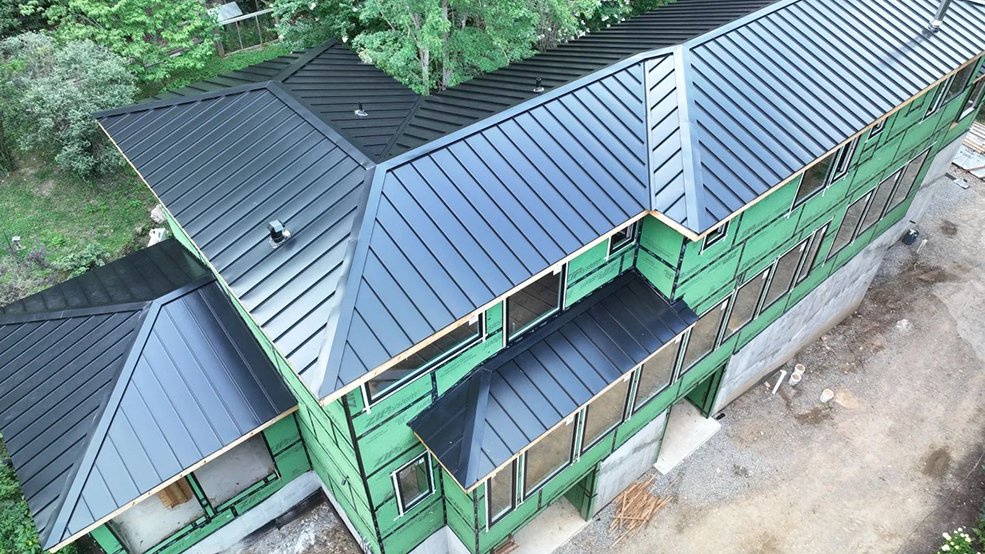 Black standing seam metal roof under heavy tree cover in McMinnville, TN