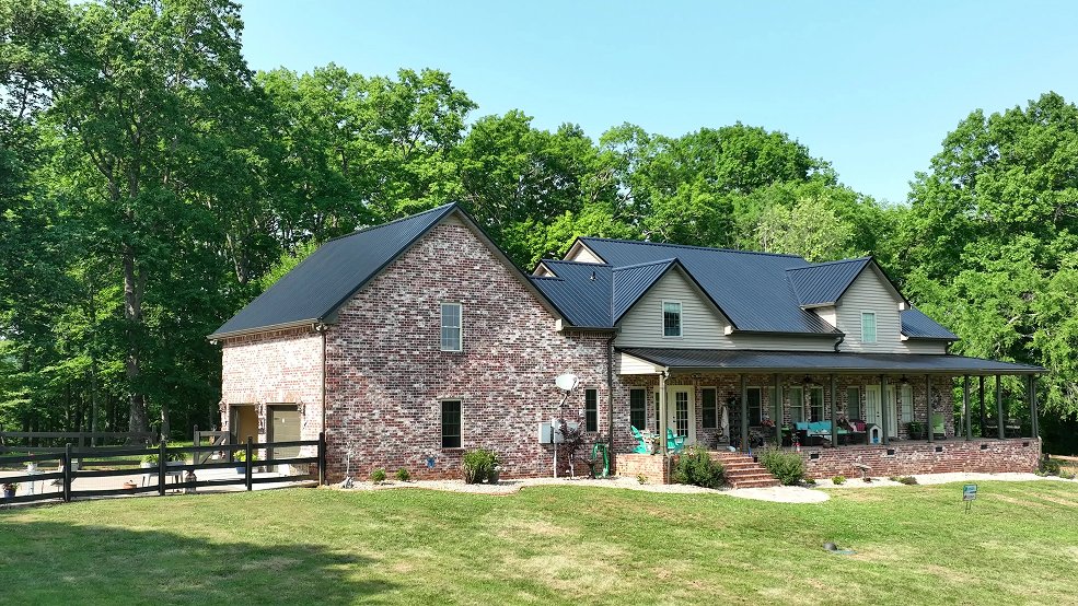 Black standing seam metal roof on a country home set on a pasture hill in Columbia, Tennessee