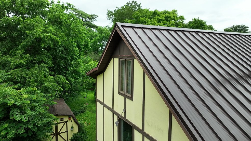 Mansard brown standing seam metal roof and dormers on a Tudor home in Brentwood, Tennessee
