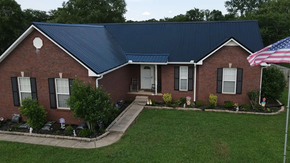 Black traditional exposed fastener metal panel roof with an American flag