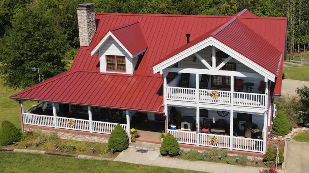 Red standing seam metal roof panels running to the ridge