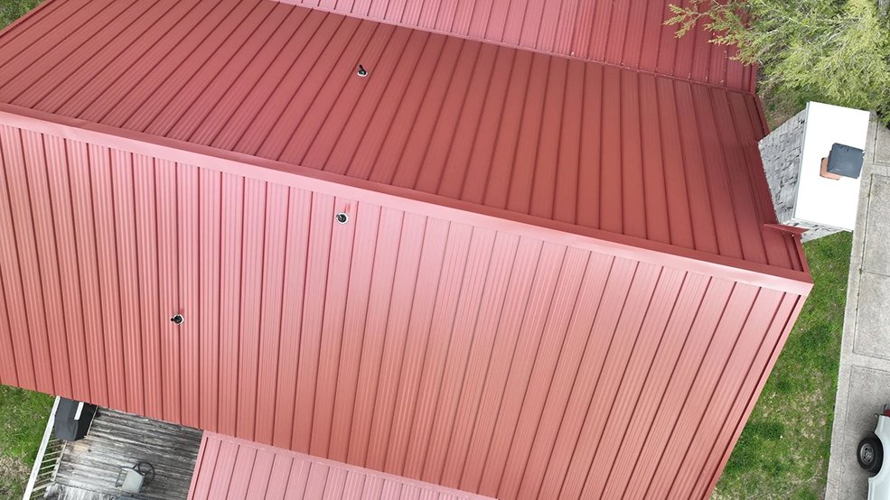 Red standing seam metal roof panels and ridge cap