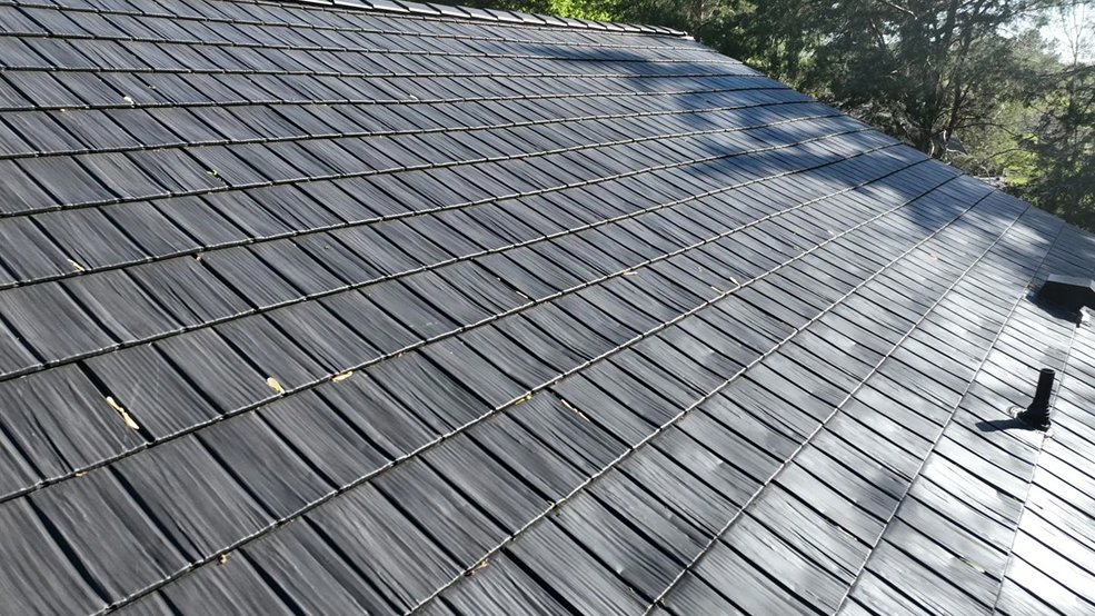 Gray metal roof and backyard elevation of a blue home in Portland, Tennessee