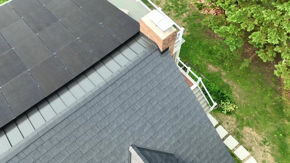 Wide view of black steel shingles and standing seam panels with a solar array