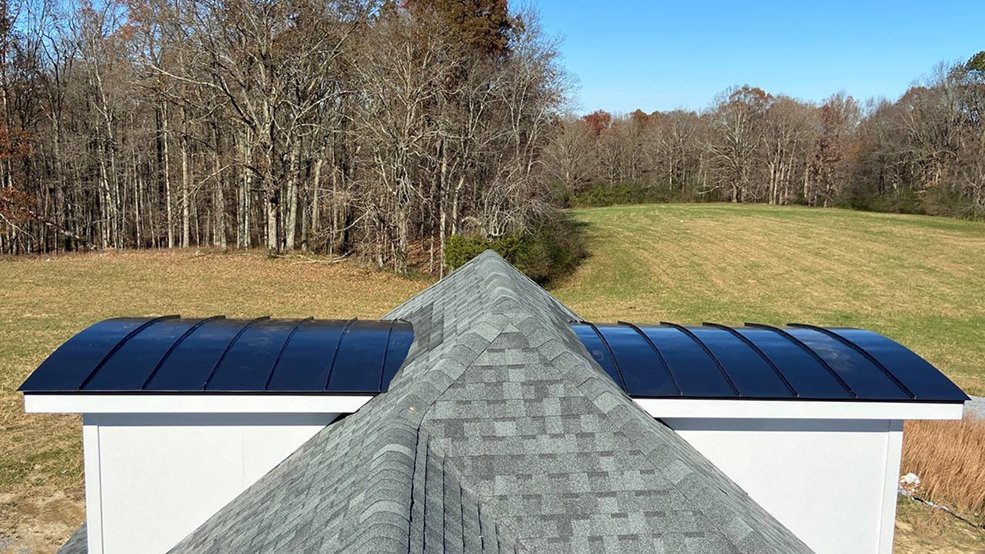 Curved black standing seam panels formed over rounded gables