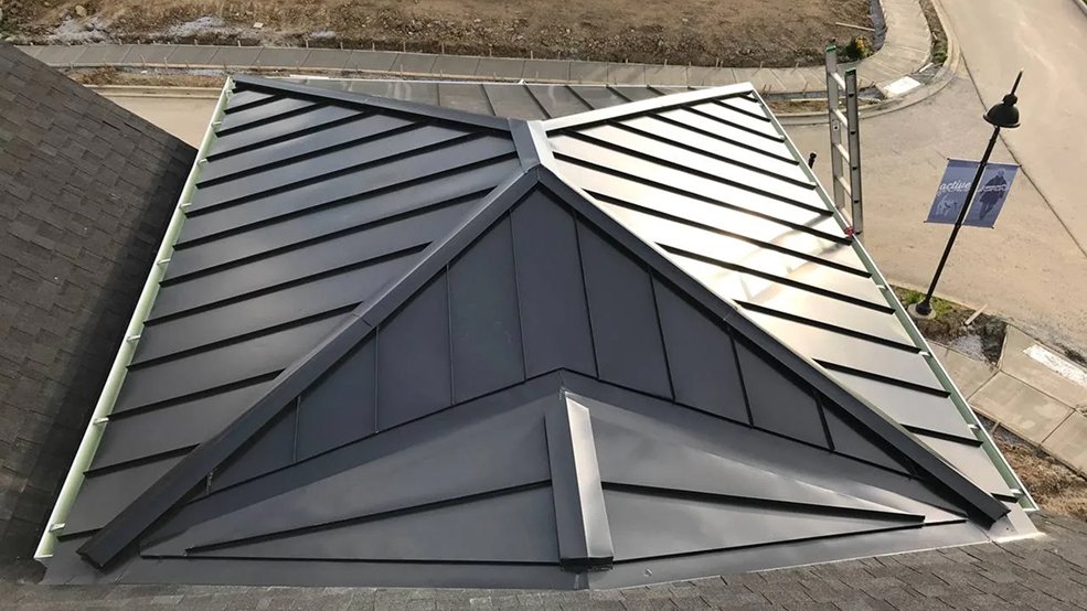 Black standing seam metal panels formed around a turret