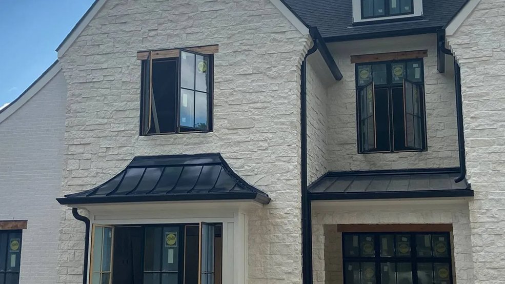 Curved black standing seam panels formed over dormers