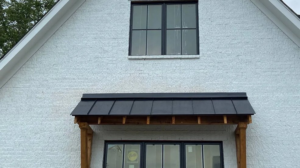 Black standing seam metal roof formed around a dormer
