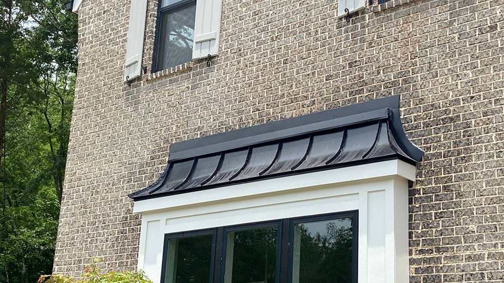 Curved black standing seam panels formed over a dormer
