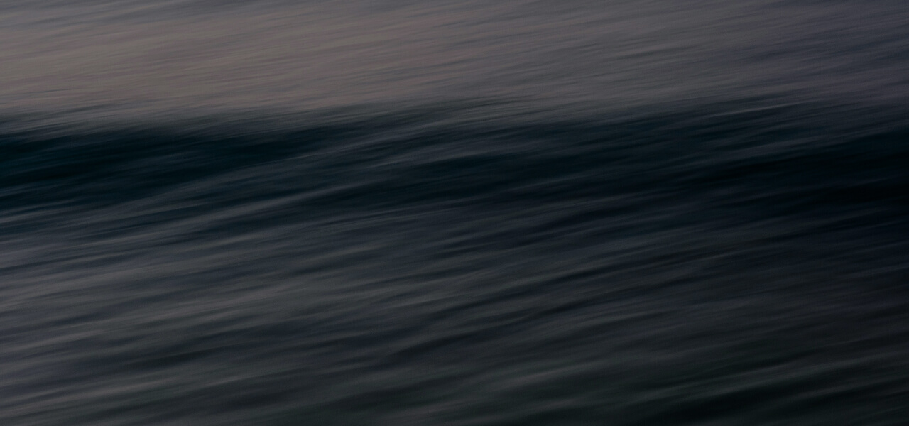 Close-up of gently rippling dark water surface with soft reflections.