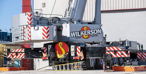 Wilkerson Crane Rental mobile crane with black and red striped safety markings parked at an industrial site.