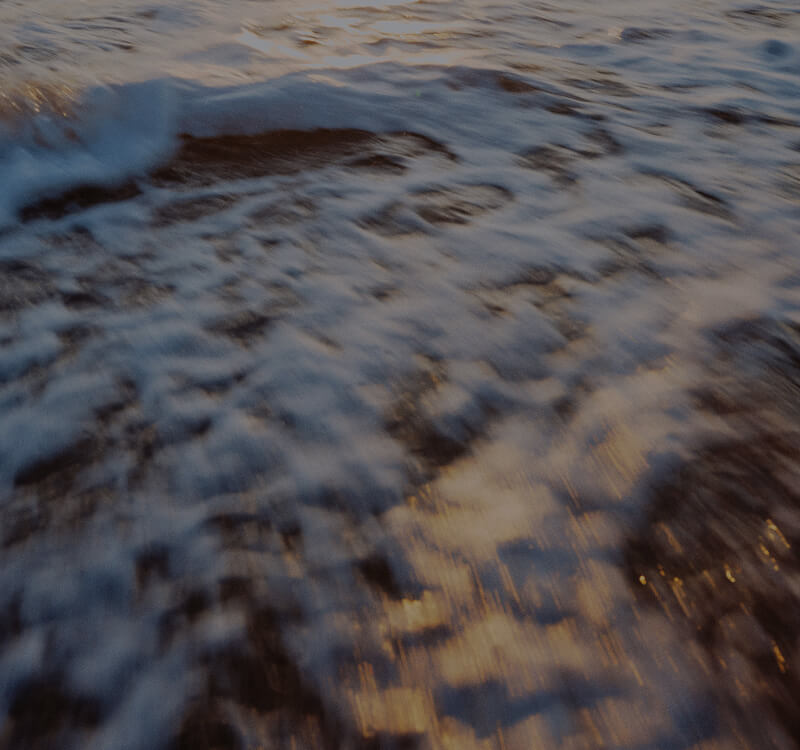Blurred motion of two cars passing on a paved road captured from above during daylight.
