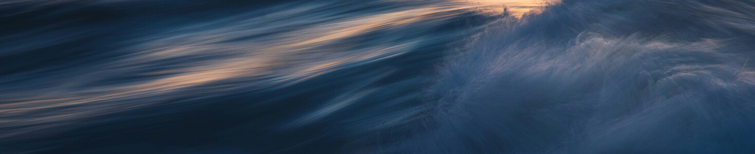 Calm ocean waves with sunlight reflecting on the water surface during sunset.