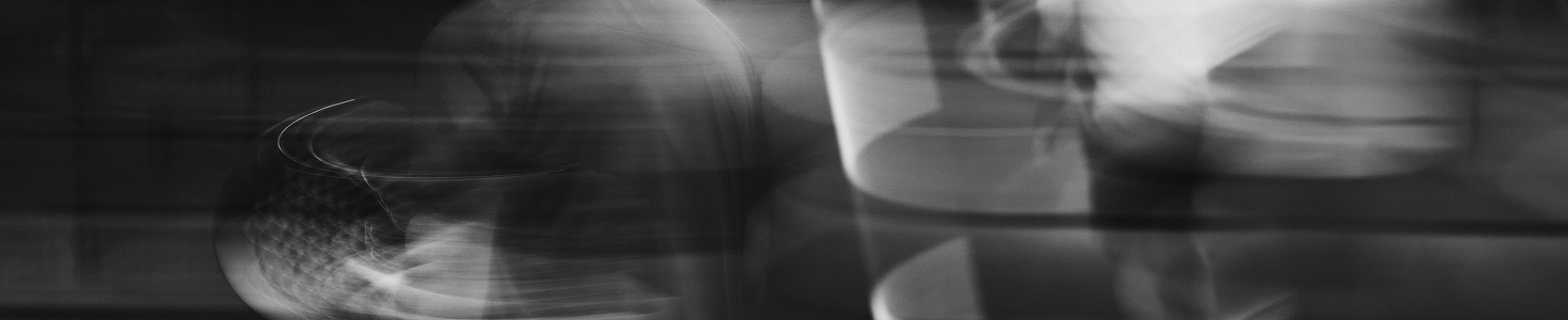 Abstract black and white image with blurred, swirling light and shadow patterns.