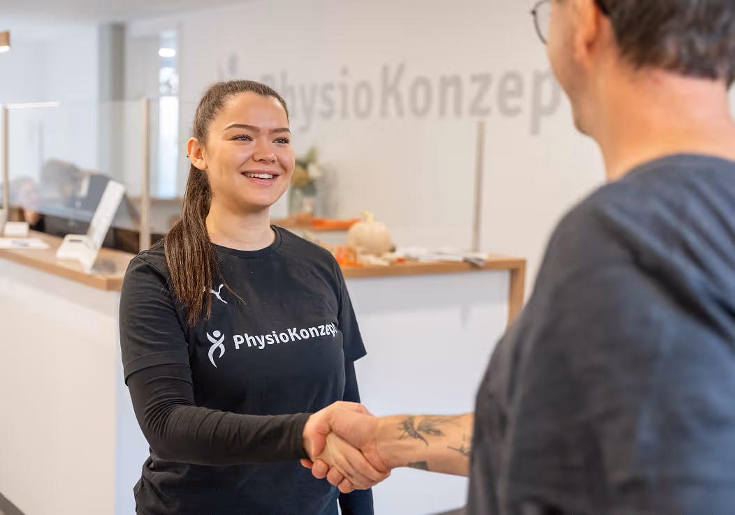 Physiotherapeutin von PhysioKonzept begrüßt einen Patienten am Empfang der Praxis