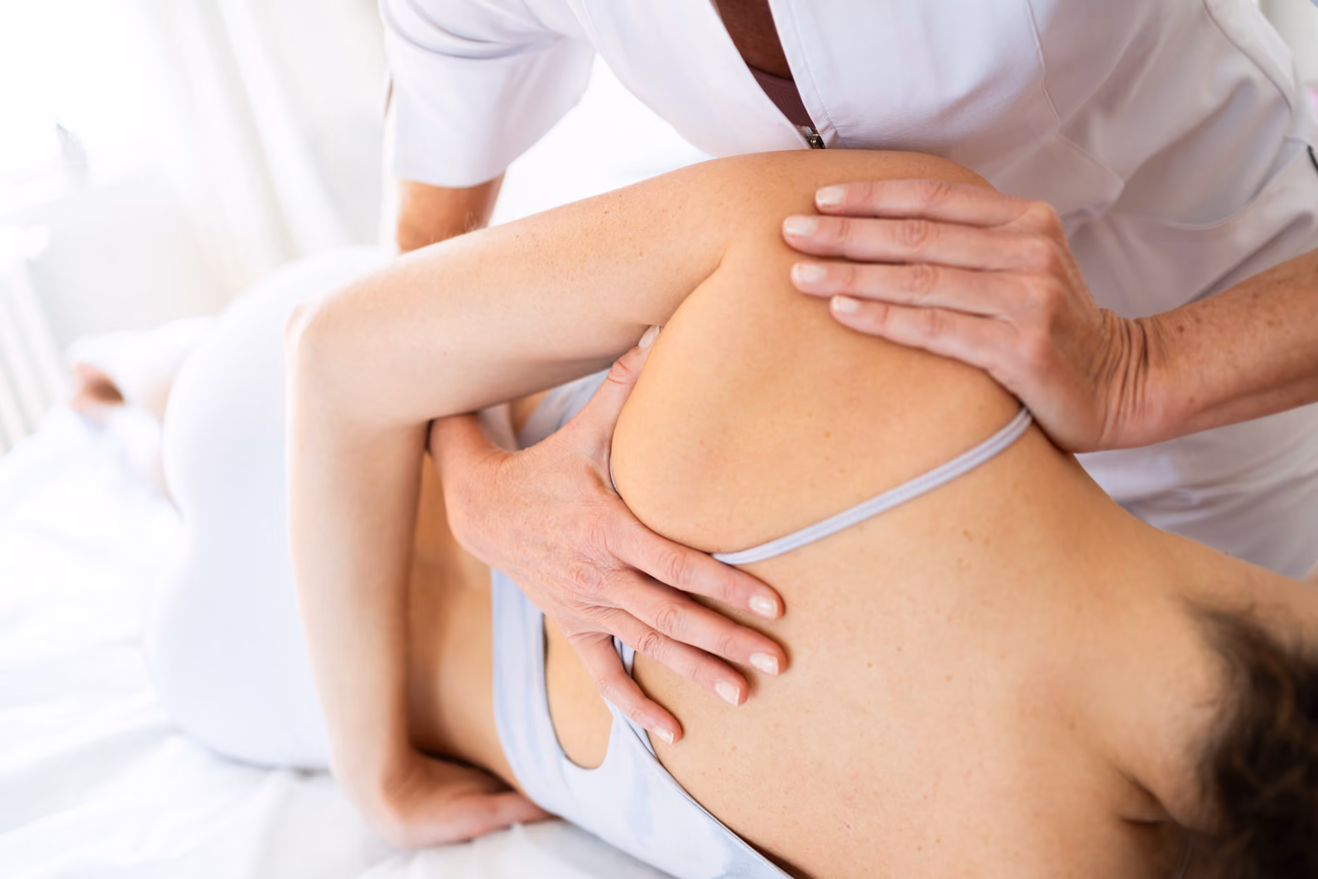 Therapeutin mobilisiert das Schultergelenk einer Patientin bei der Manuellen Therapie