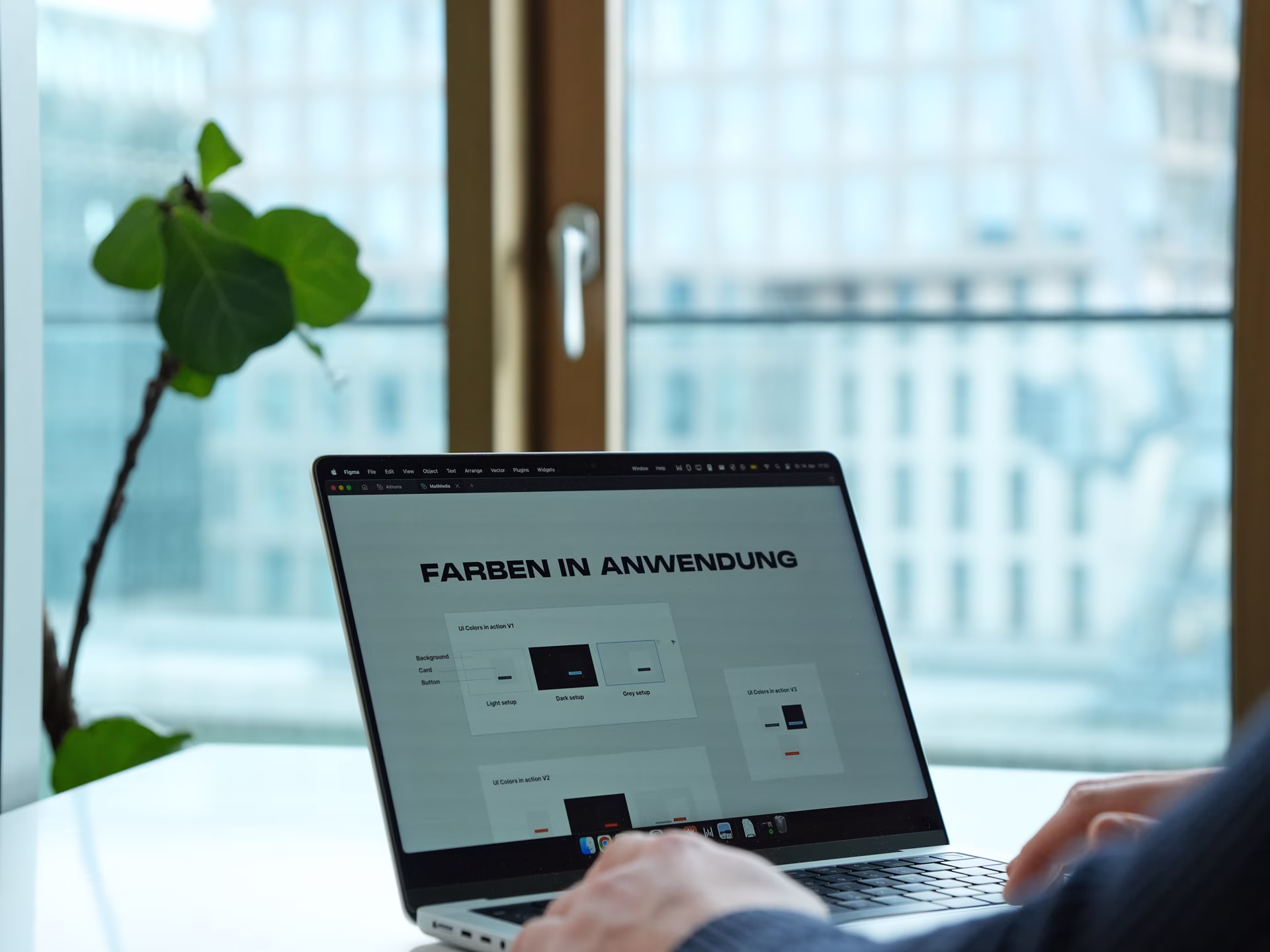 Person working on a laptop displaying UI color scheme options titled 'FARBEN IN ANWENDUNG'.
