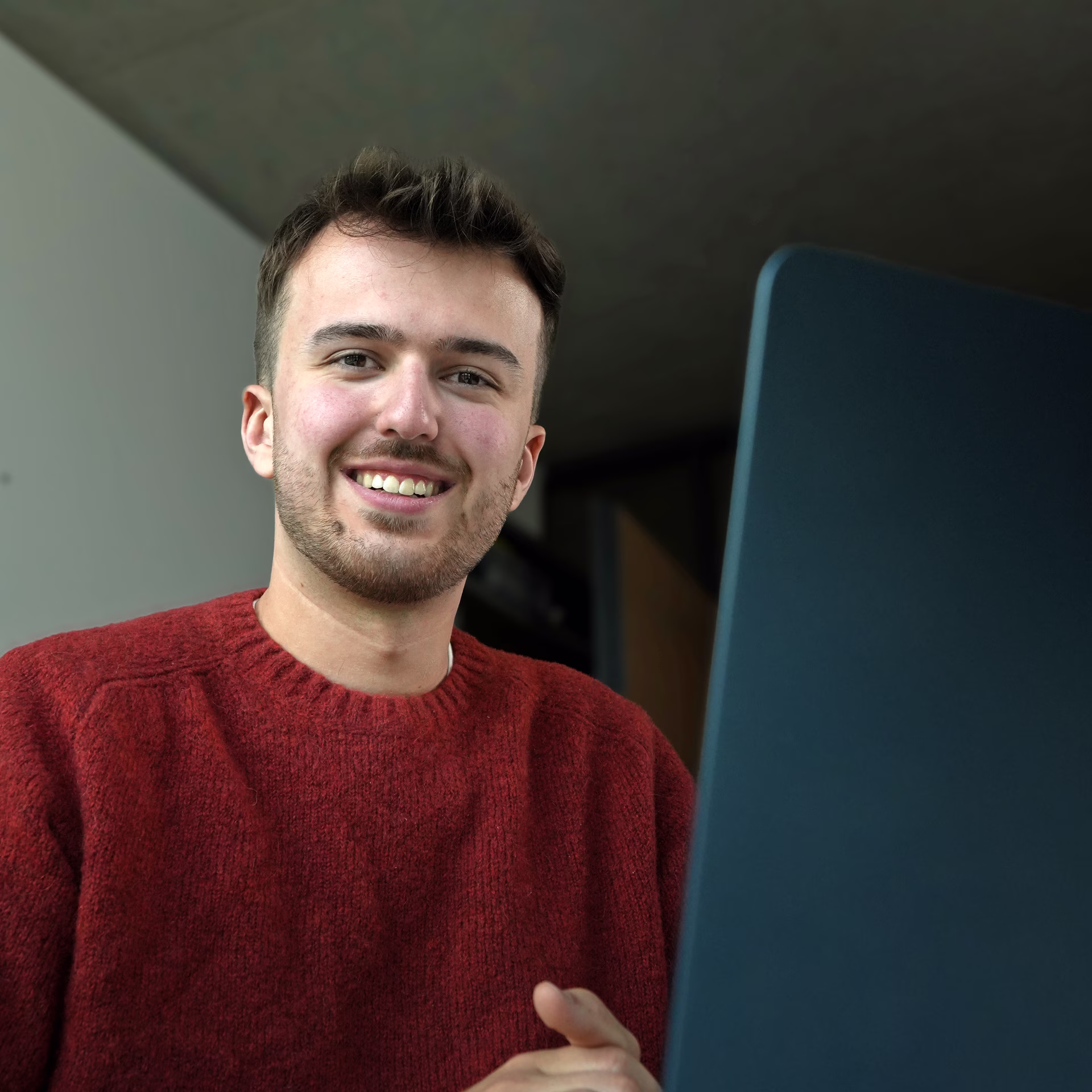Luca Skunca lächelnd am Laptop im Büro am Hafen Münster